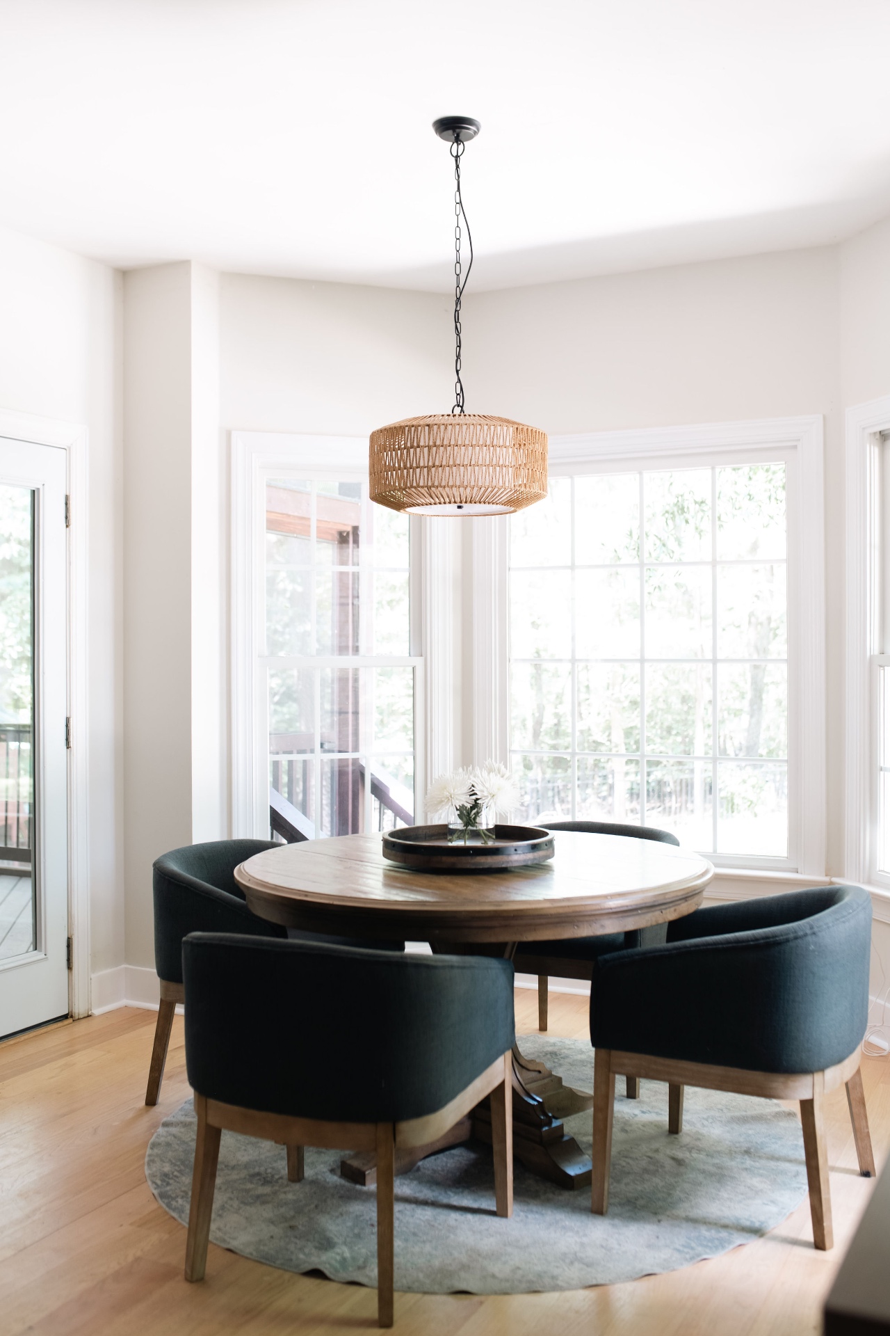 Breakfast nook overlooking the deck with bay windows and rattan pendant lighting.