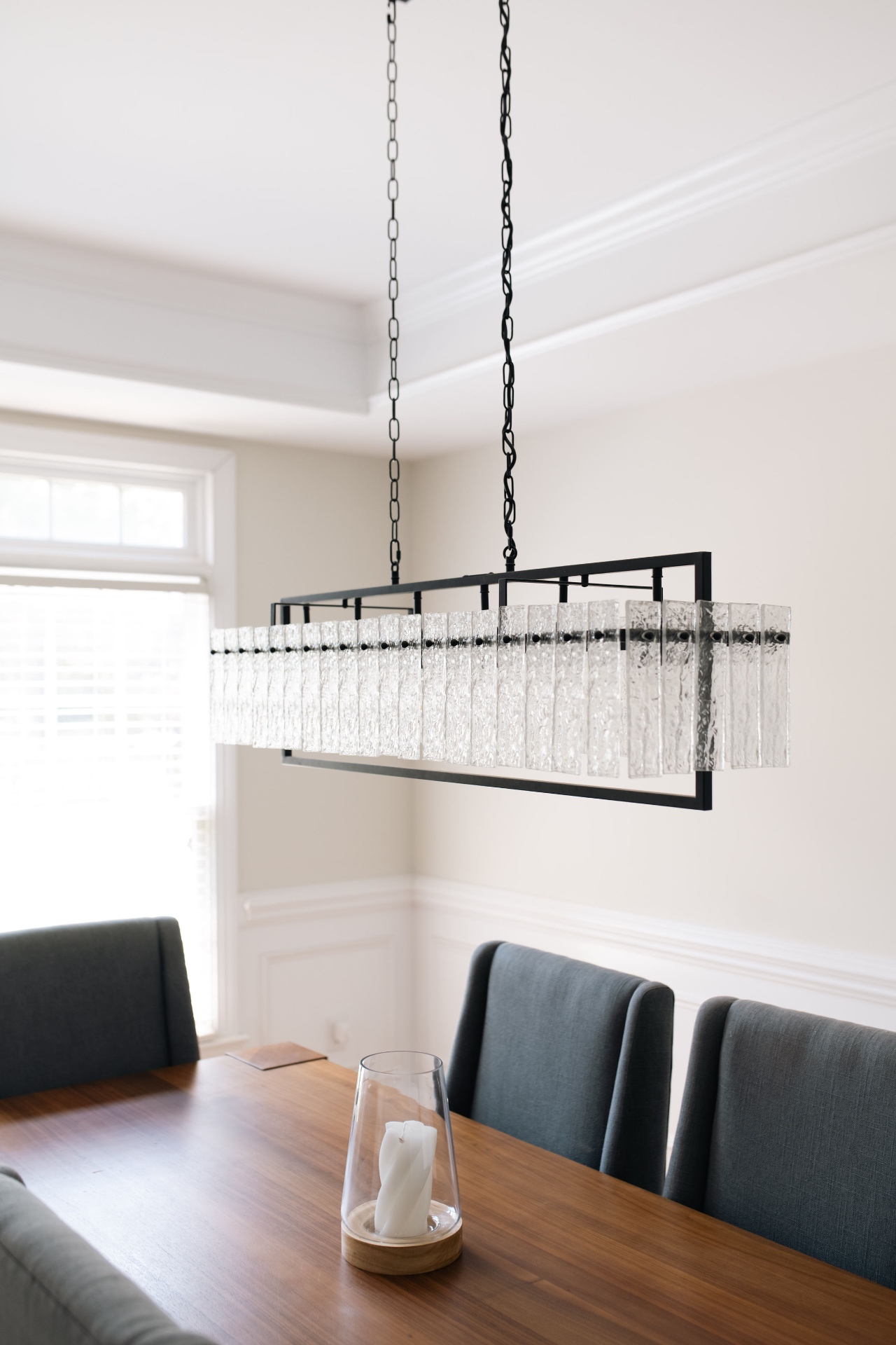 Detail of the linear crystal-and-iron chandelier above the walnut dining table.