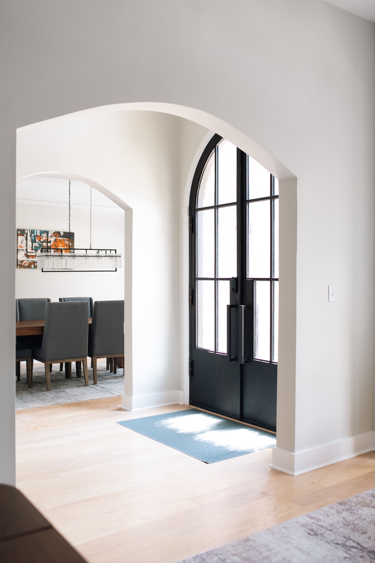 Sculptural archway framing the arched steel front doors with formal dining room beyond.