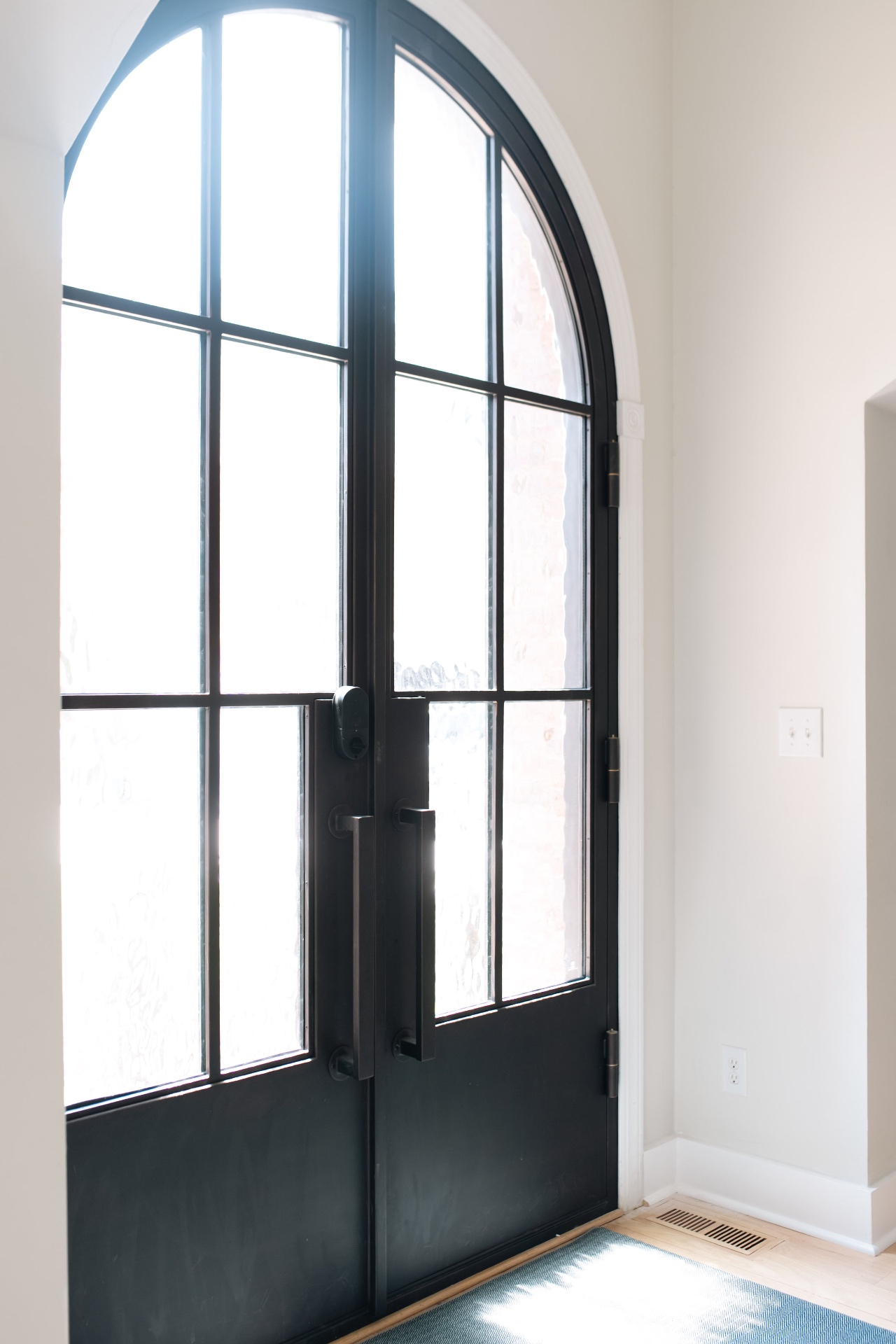 Interior view of the arched steel double front doors flooded with natural light.