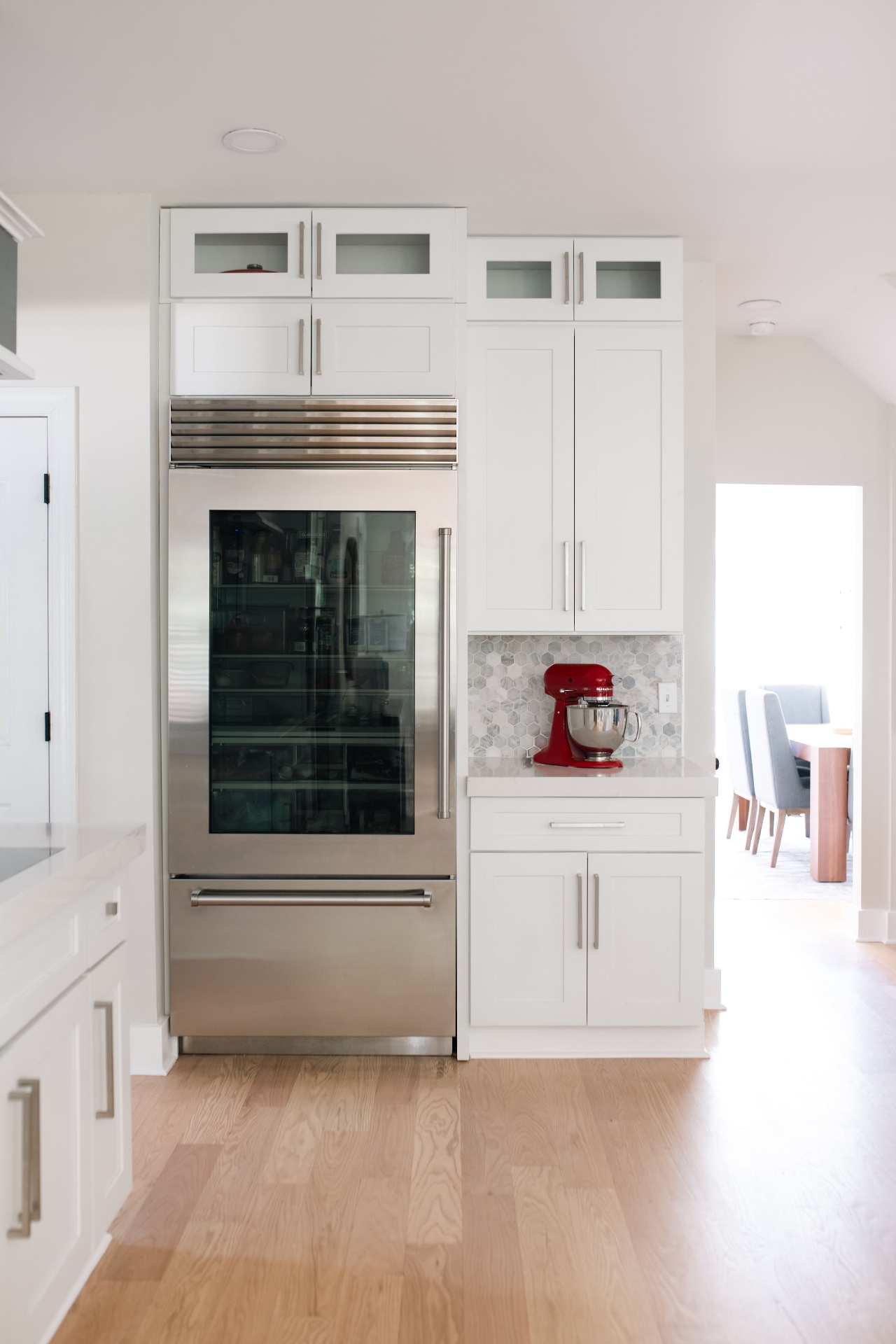 Chef's kitchen with Sub-Zero glass-front refrigerator and custom white cabinetry.