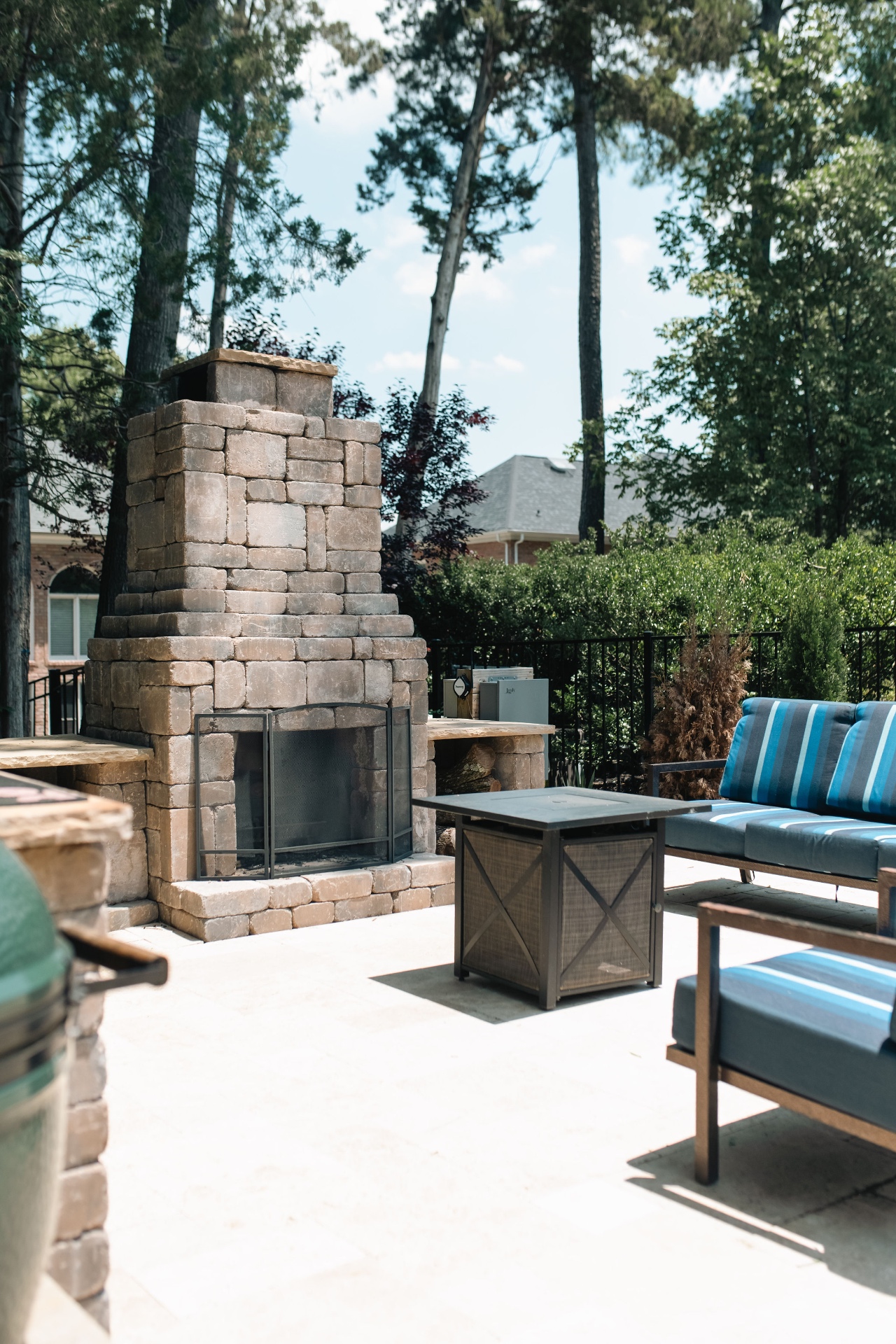 Stone outdoor fireplace anchoring the patio lounge with cushioned seating and propane fire table.
