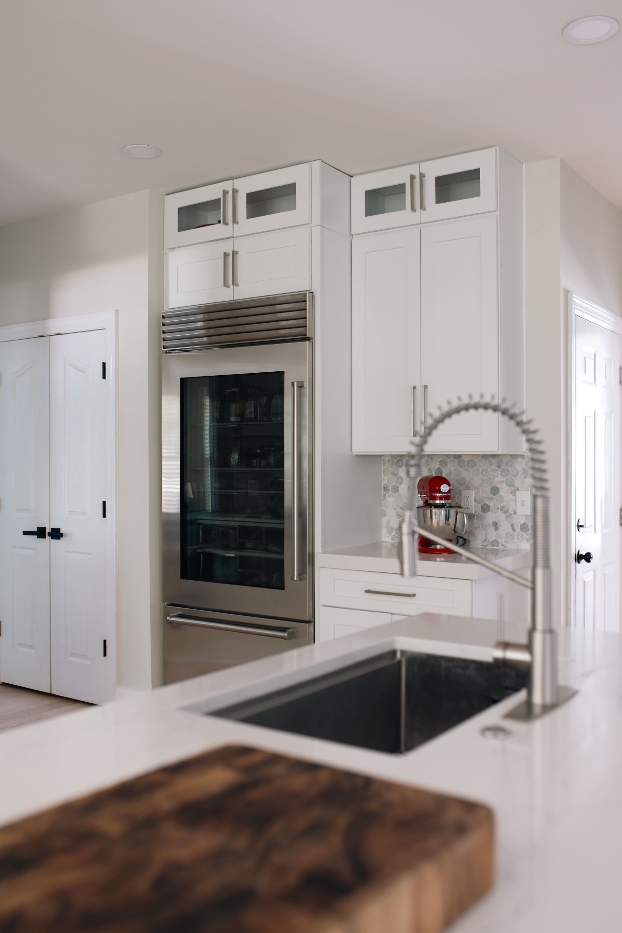 Kitchen island sink looking toward the glass-front Sub-Zero refrigerator and custom cabinetry.