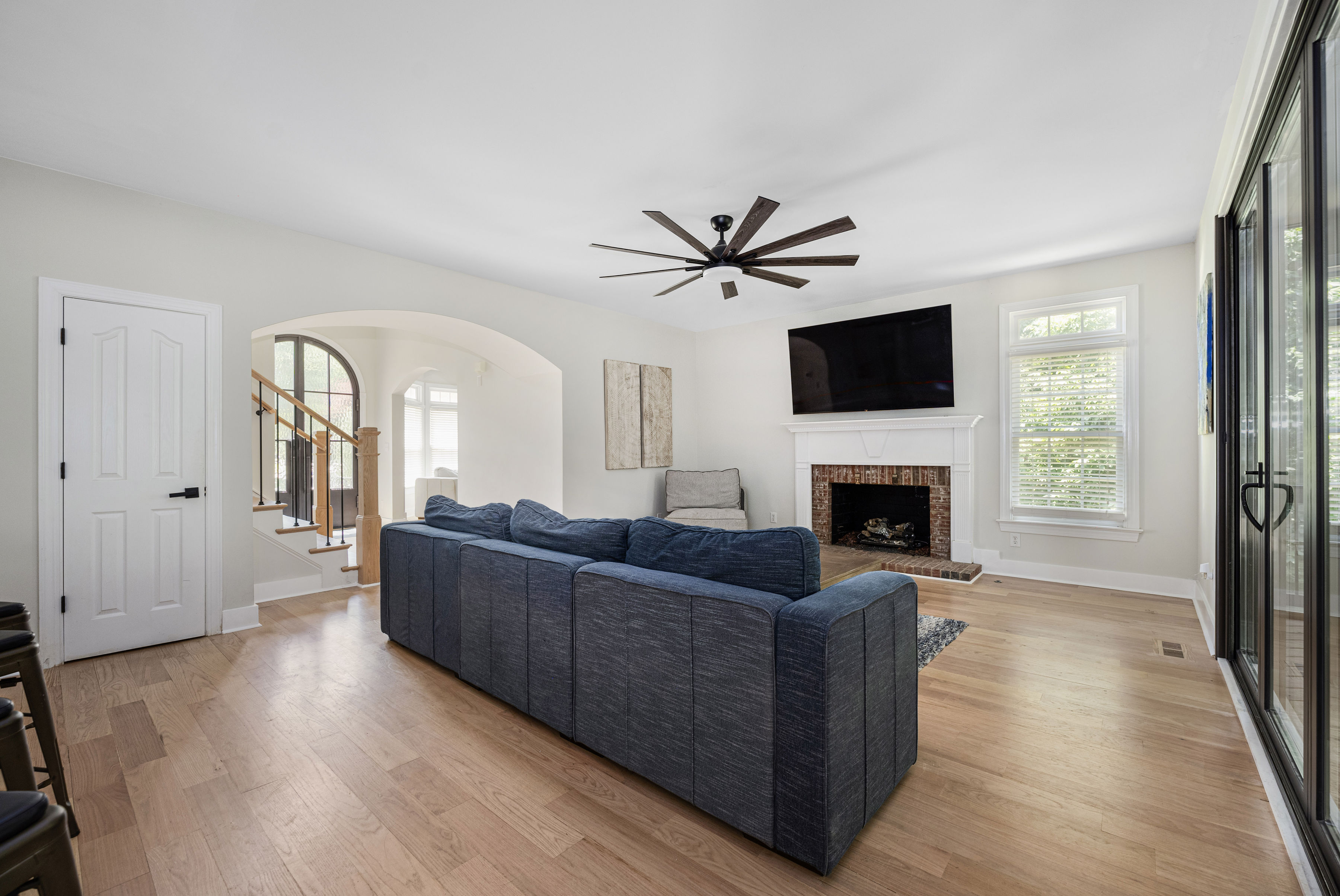 Living room with bifold doors opening to the kitchen, featuring a fireplace and an elegant archway from the entry