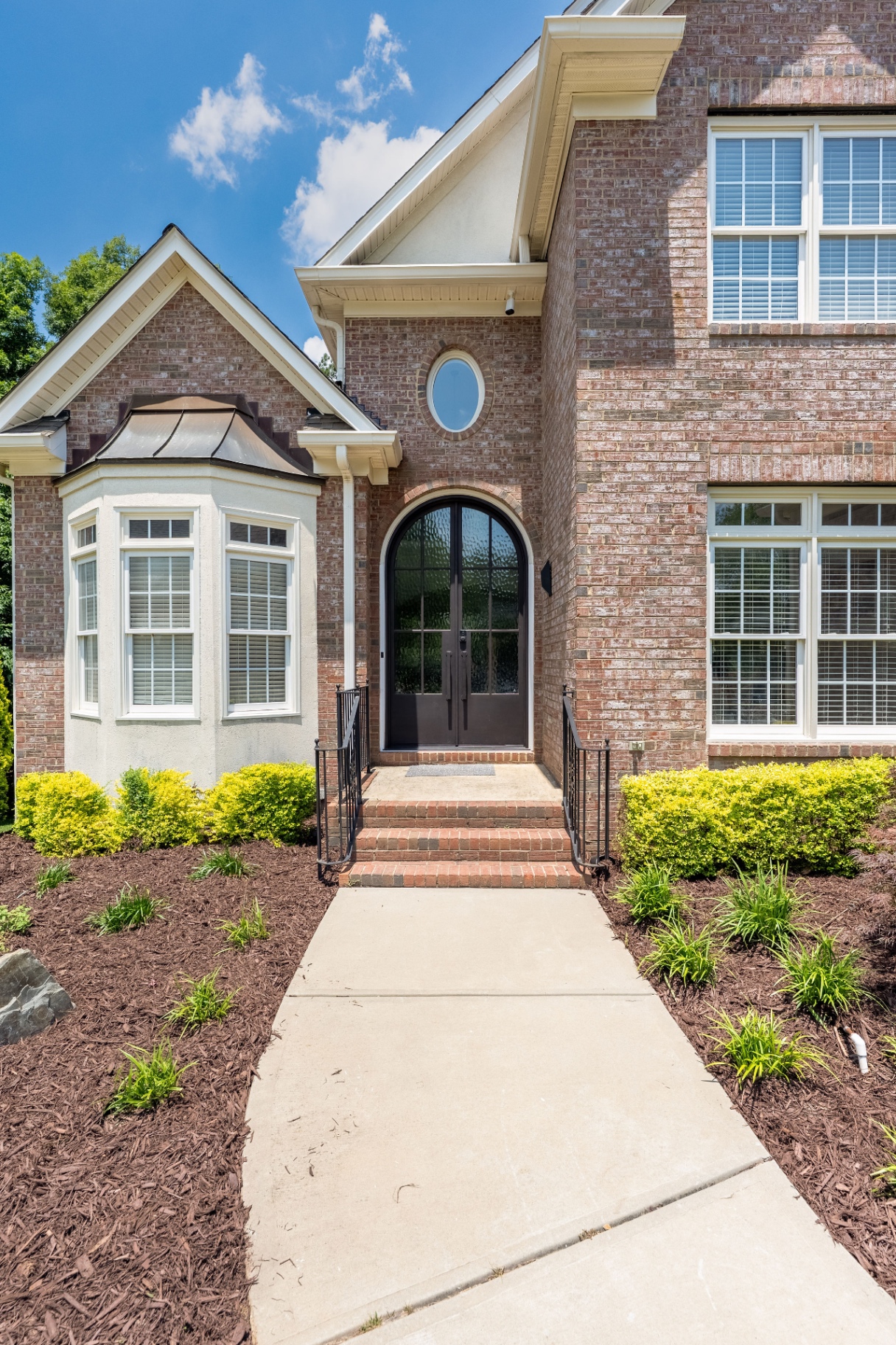 Close-up of the custom arched steel front door and landscaped entry walk.