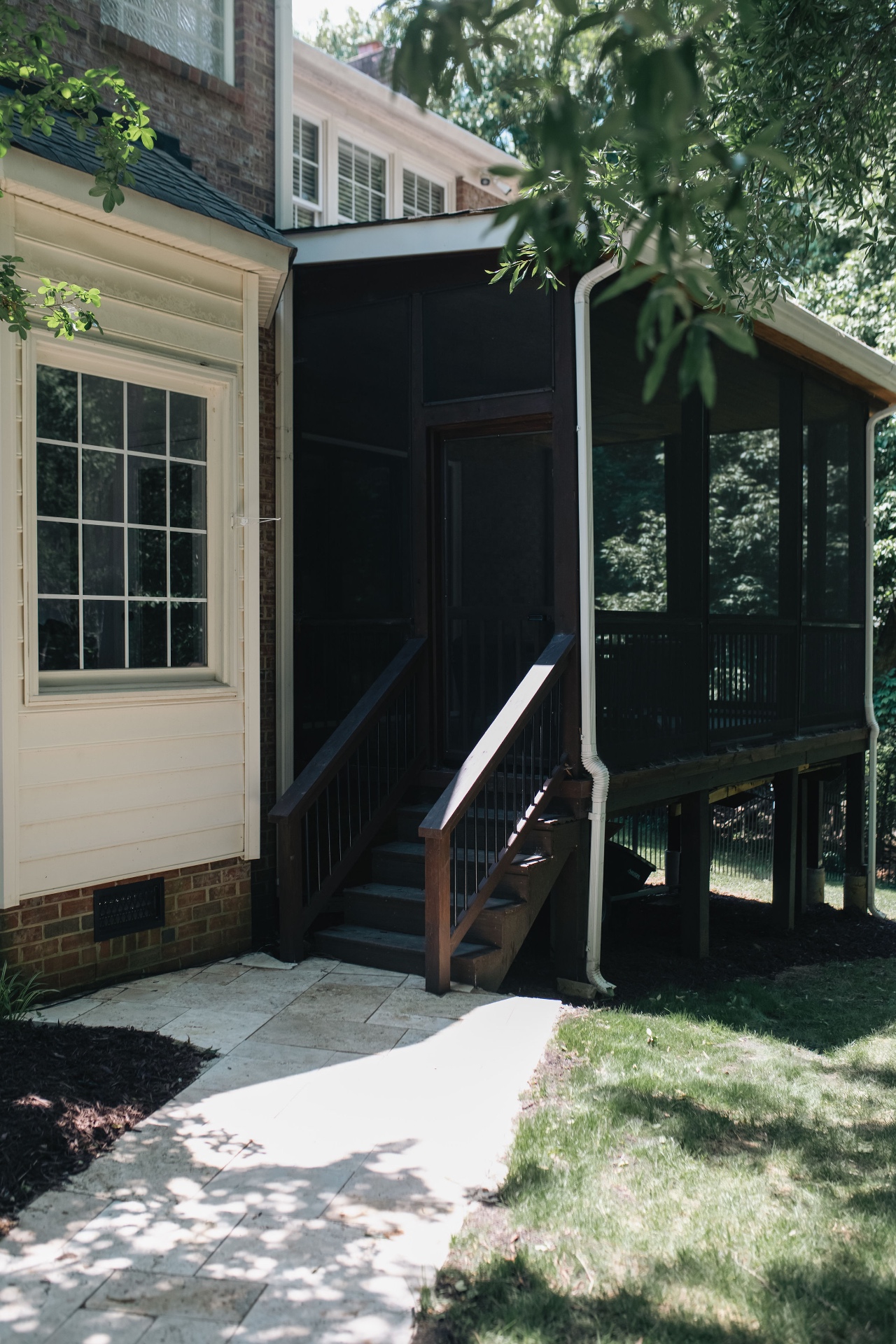 Exterior view of the screened porch and rear staircase leading down to the patio.
